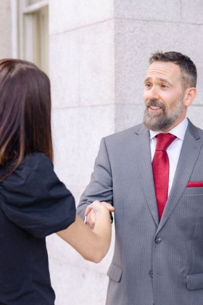 John Montagna smiling shaking hands with a personal injury client after a successful case result