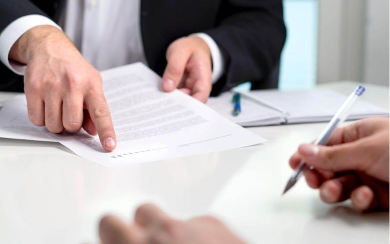 two people sitting at a table signing papers