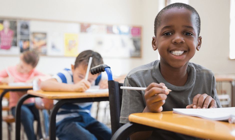 Little boy in classroom smiling sitting in wheelchair