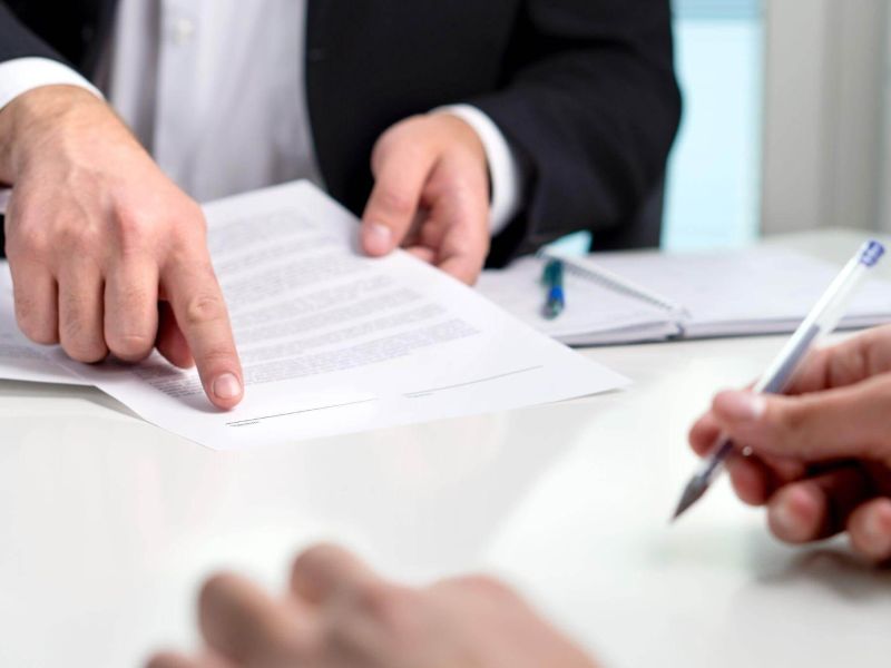 two people sitting at a table signing papers