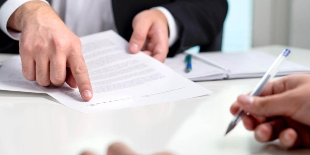 two people sitting at a table signing papers