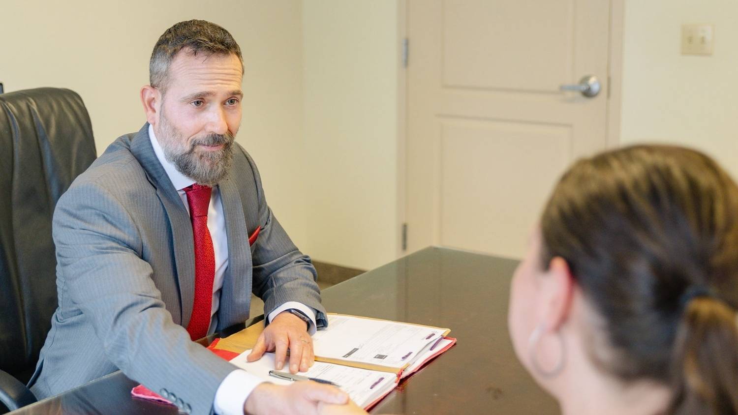 Jon Montagna personal injury lawyer shakes the hand of a client as they sit in front of a desk