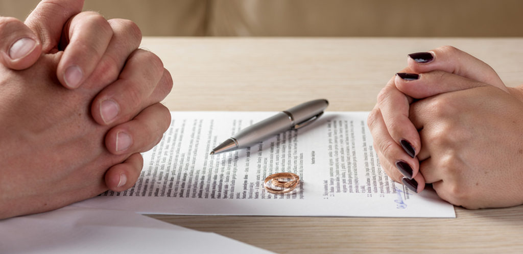 man and woman resting their hands on a paper next to wedding rings