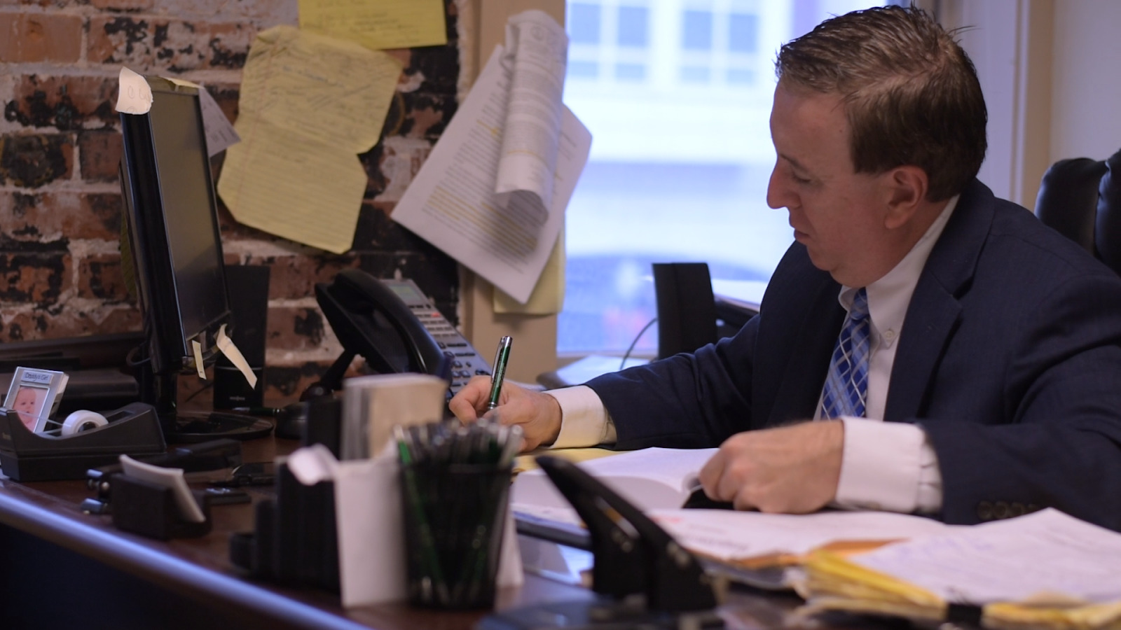 man wearing a suit sitting at a desk writing in a journal