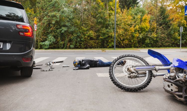 man laying on ground next to motorcycle
