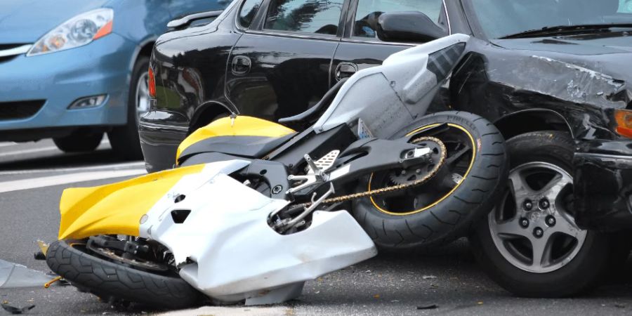 Yellow and white motorcycle on its side next to car after collision accident
