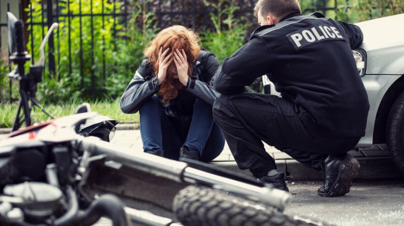 Woman with hands on face next to police officer