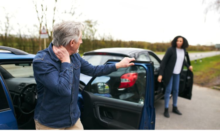 Man holding neck while exiting a car