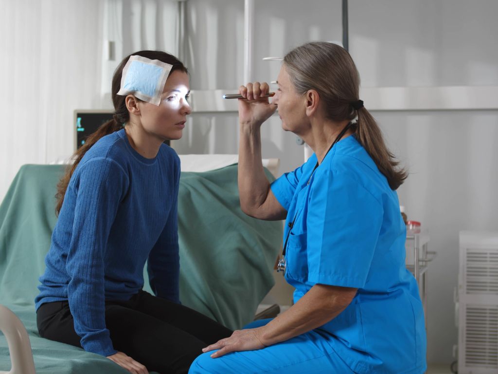 Woman sitting down having her eyes examined by a doctor