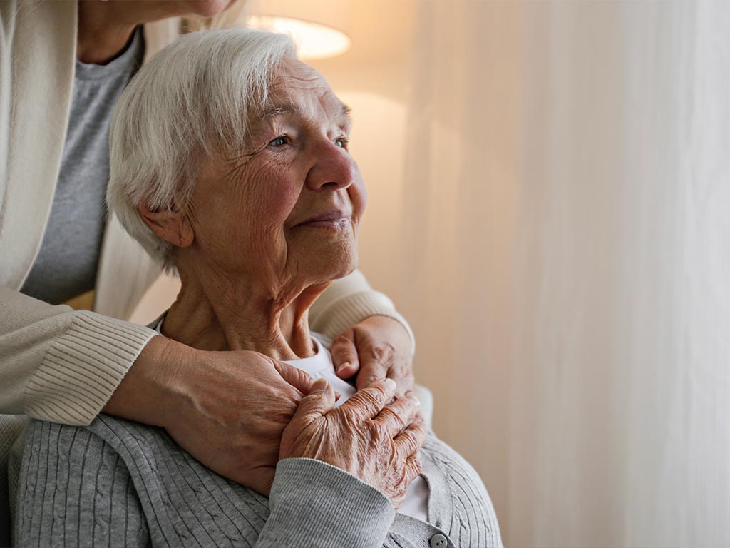 elderly woman getting a hug from behind
