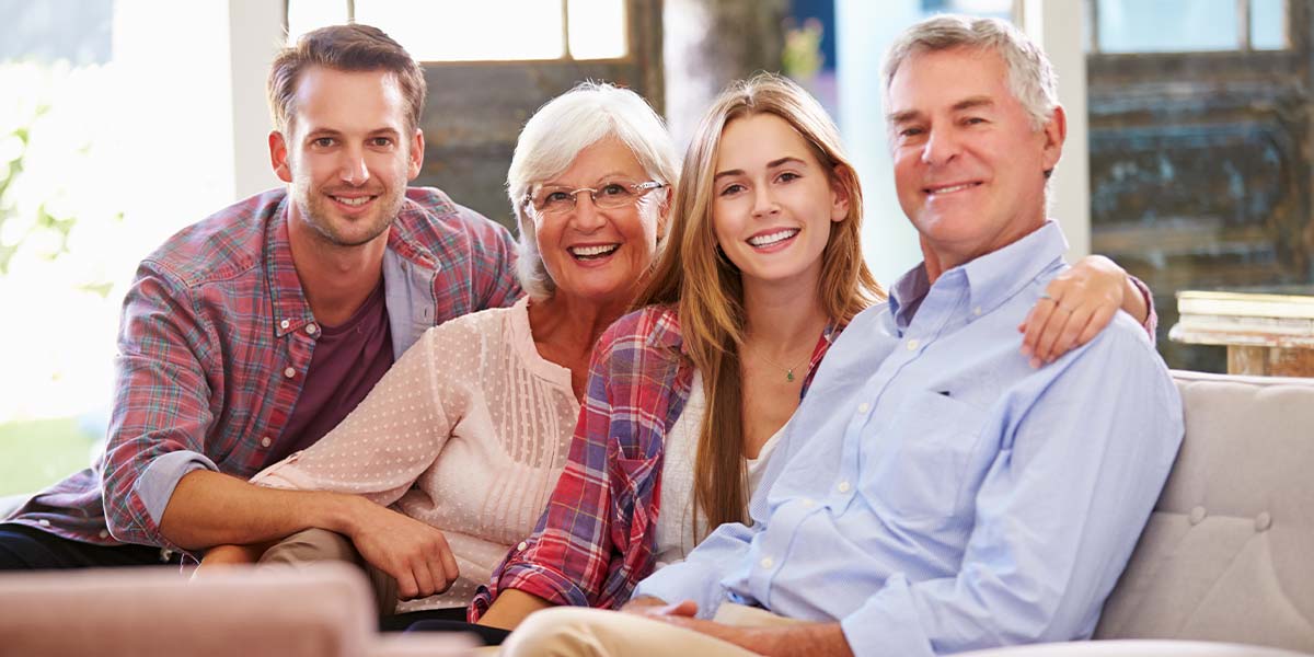 a mother and father sitting on the couch with their two adult children