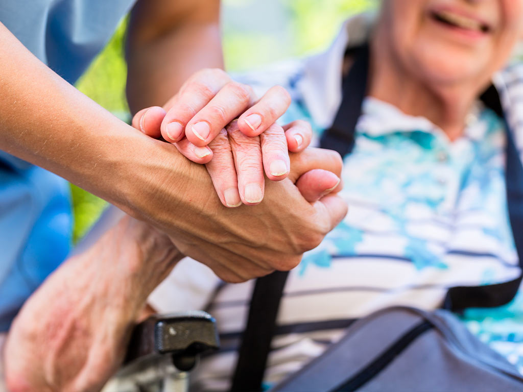 nurse holding hands with an elderly woman