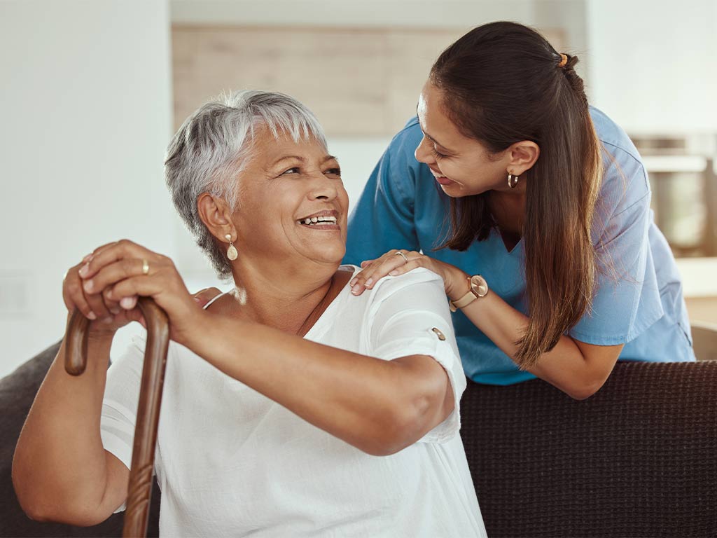 Nurse smiling while looking at an elderly woman