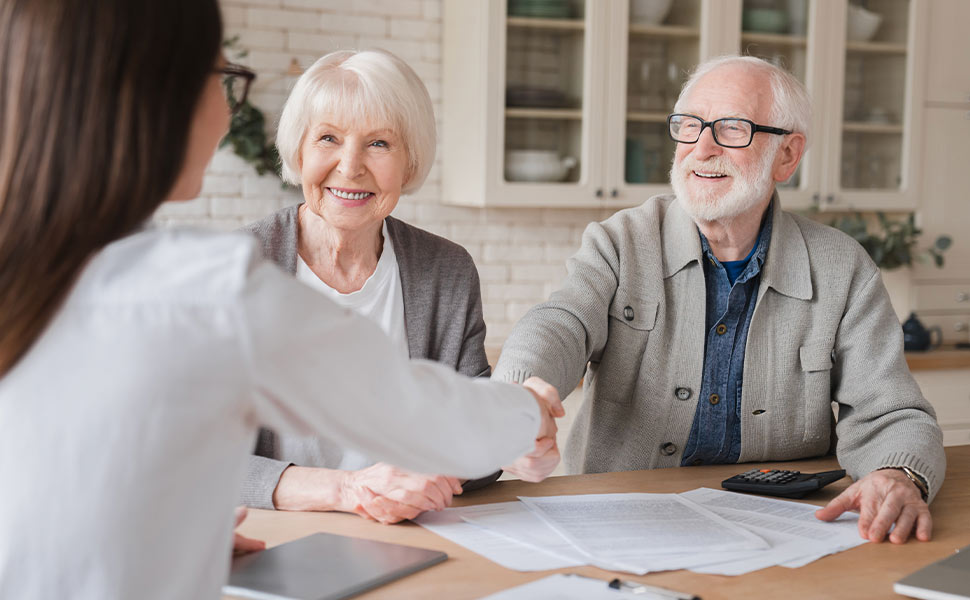 elderly couple sitting down with a lawyer and signing paperwork