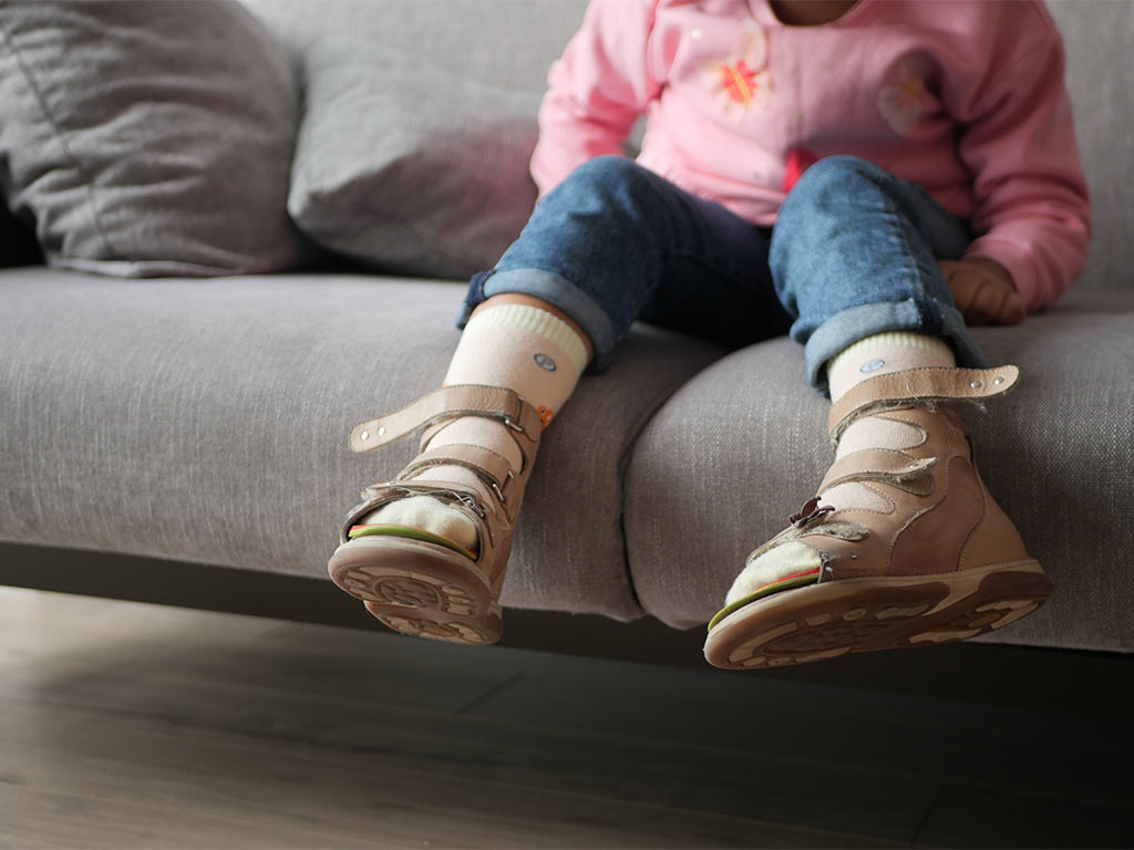 a child sitting on a couch wearing sandals
