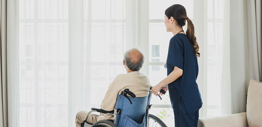 healthcare worker assisting an elderly man in a wheelchair