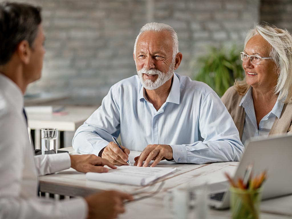 older man and woman sitting down filling out will paperwork