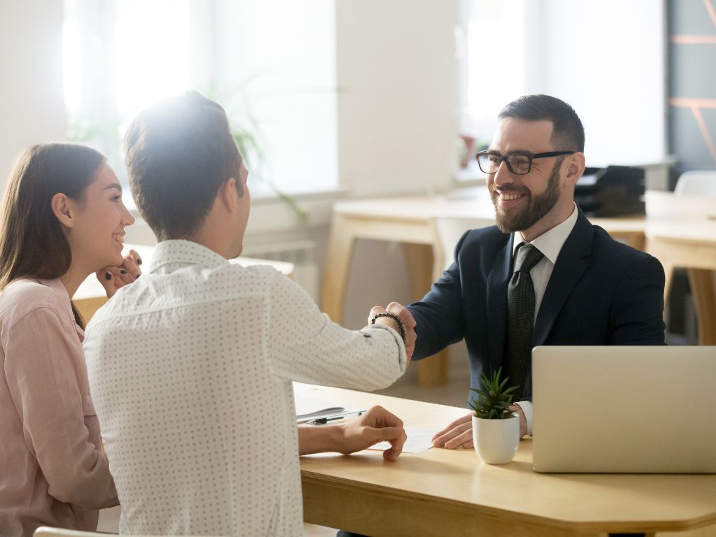 Attorney shaking hands with clients at his desk