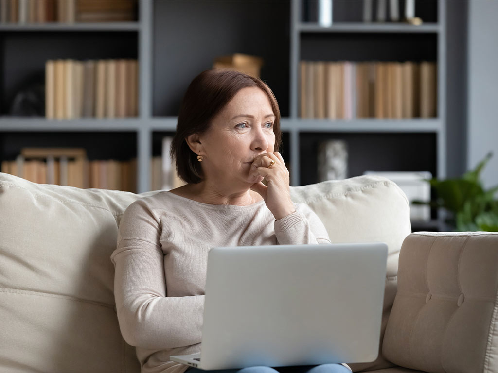 Woman sitting on her couch holding her laptop