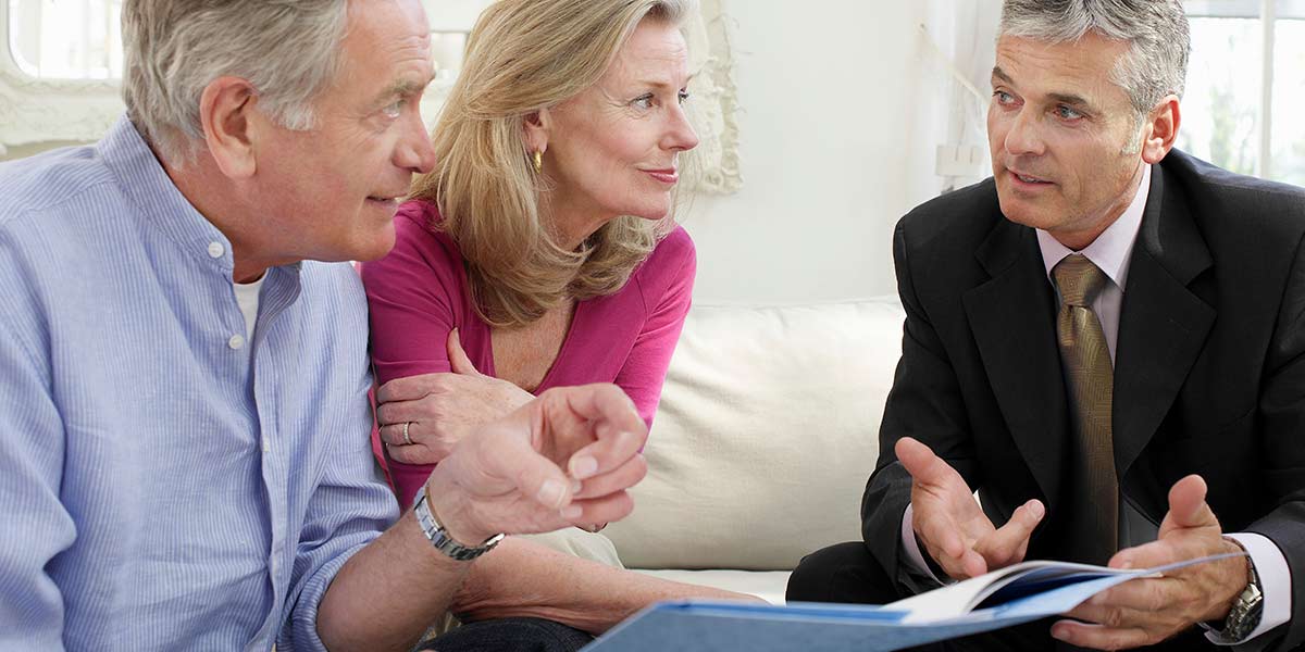 elderly couple sitting down with a trust planning attorney