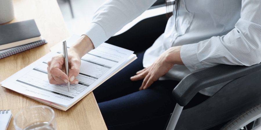 Person filling out paperwork sitting in chair wearing business attire