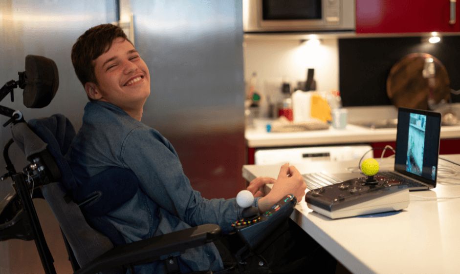 Young boy smiling in wheelchair sitting at kitchen counter