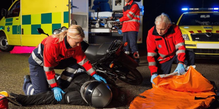 three EMTs helping motorcycle rider on the ground