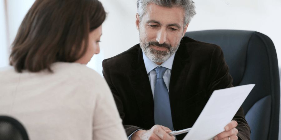 Man pointing at document with pen at a desk with woman