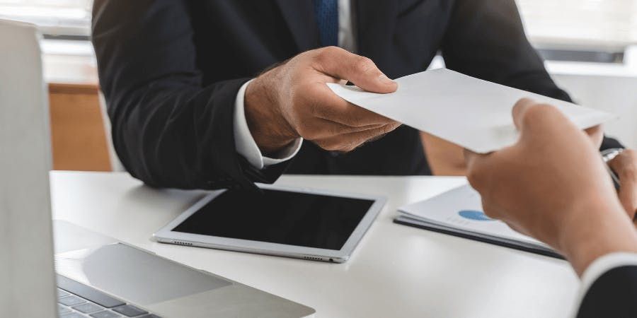 man being handed a piece of paper over a desk with tablet on it