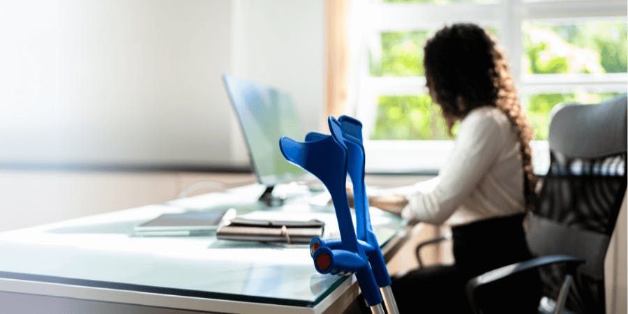 Woman at desk working with crutches leaning on desk in foreground