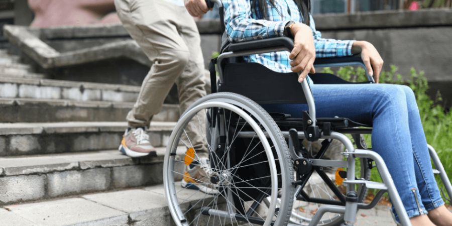 Woman in wheelchair being helped down stairs