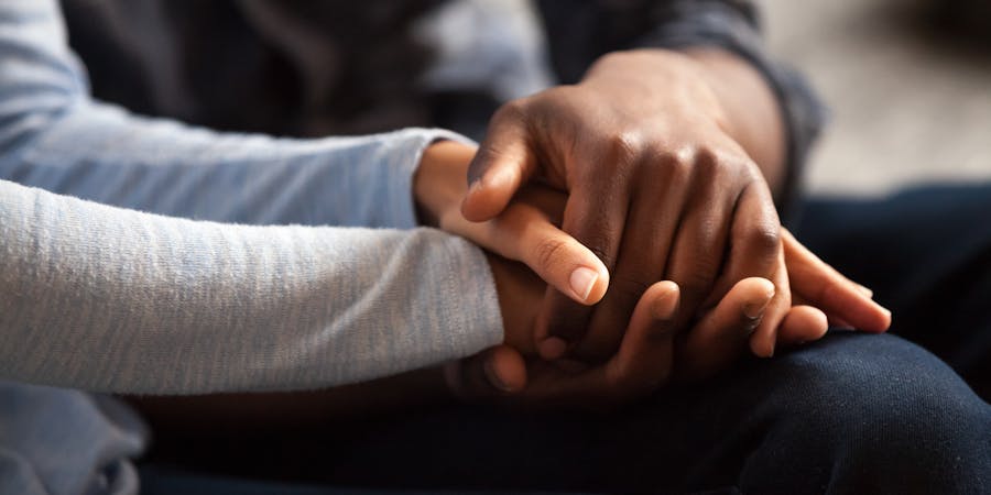 Close-up of two people holding hands, offering comfort and support, representing compassionate legal assistance during a difficult time.