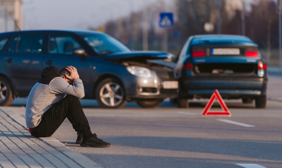 Man sitting on the curb after a car accident