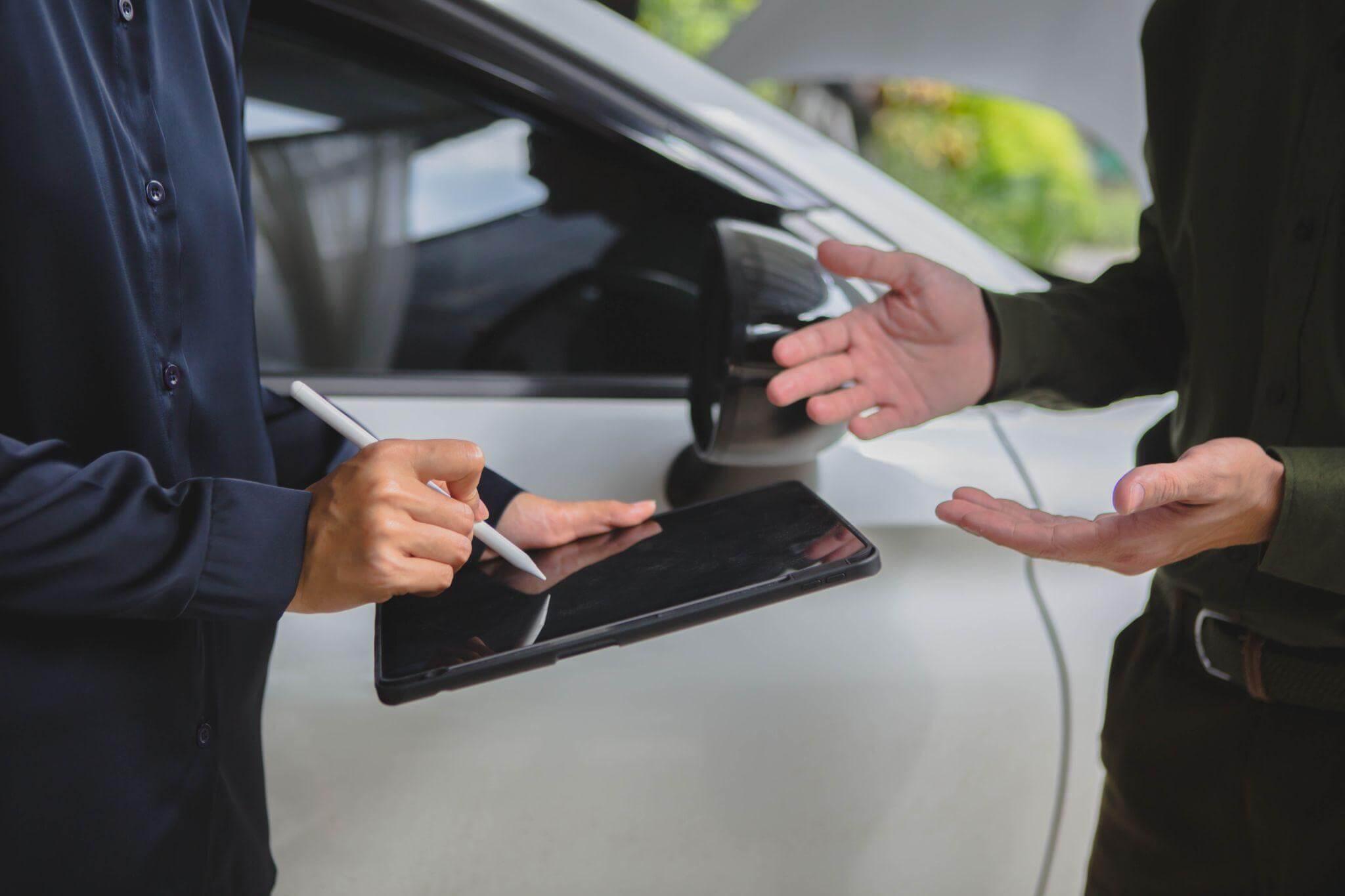 a man holding a clipboard in front of a car
