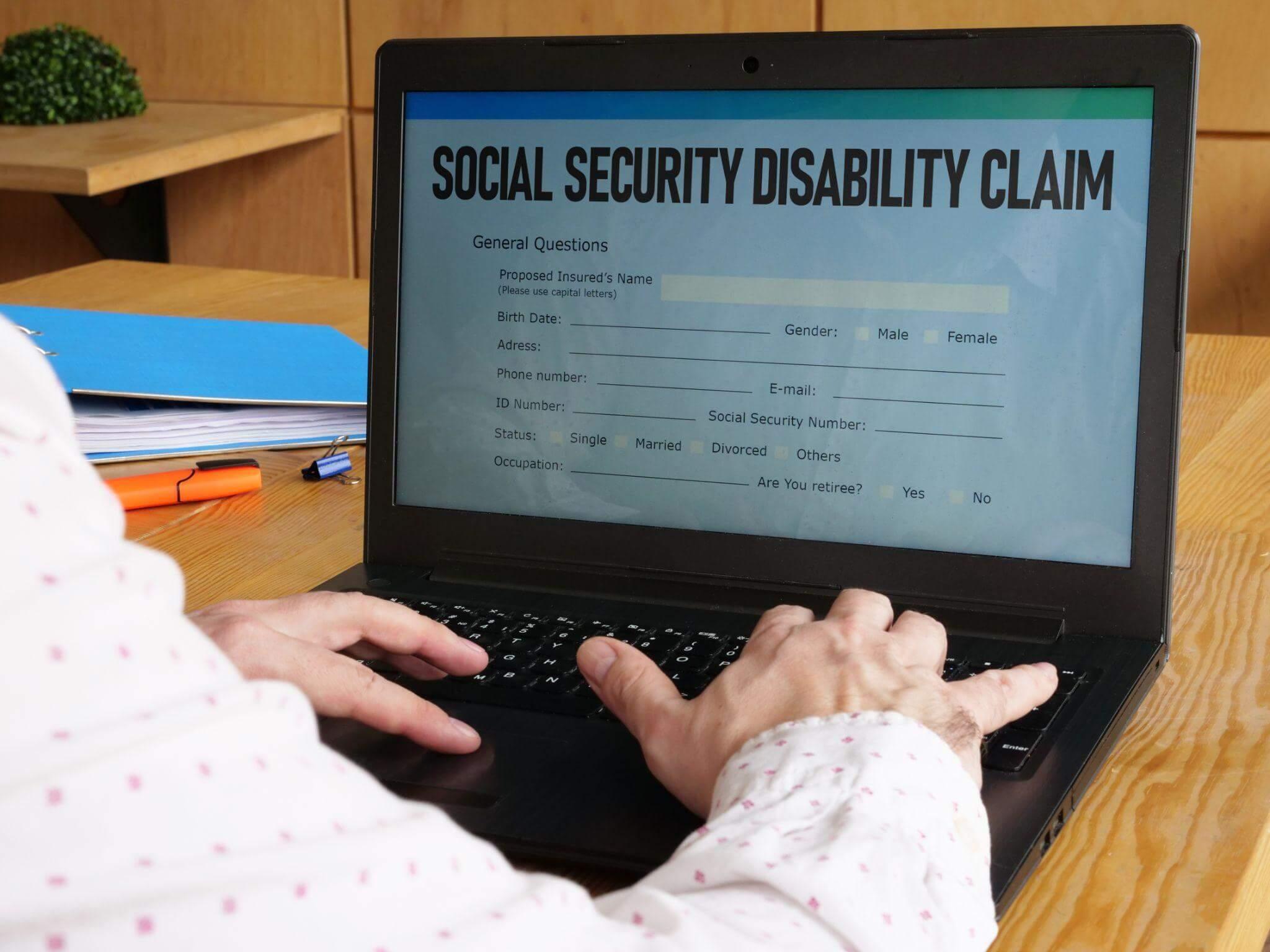 Person typing on laptop with social security disability claim displayed