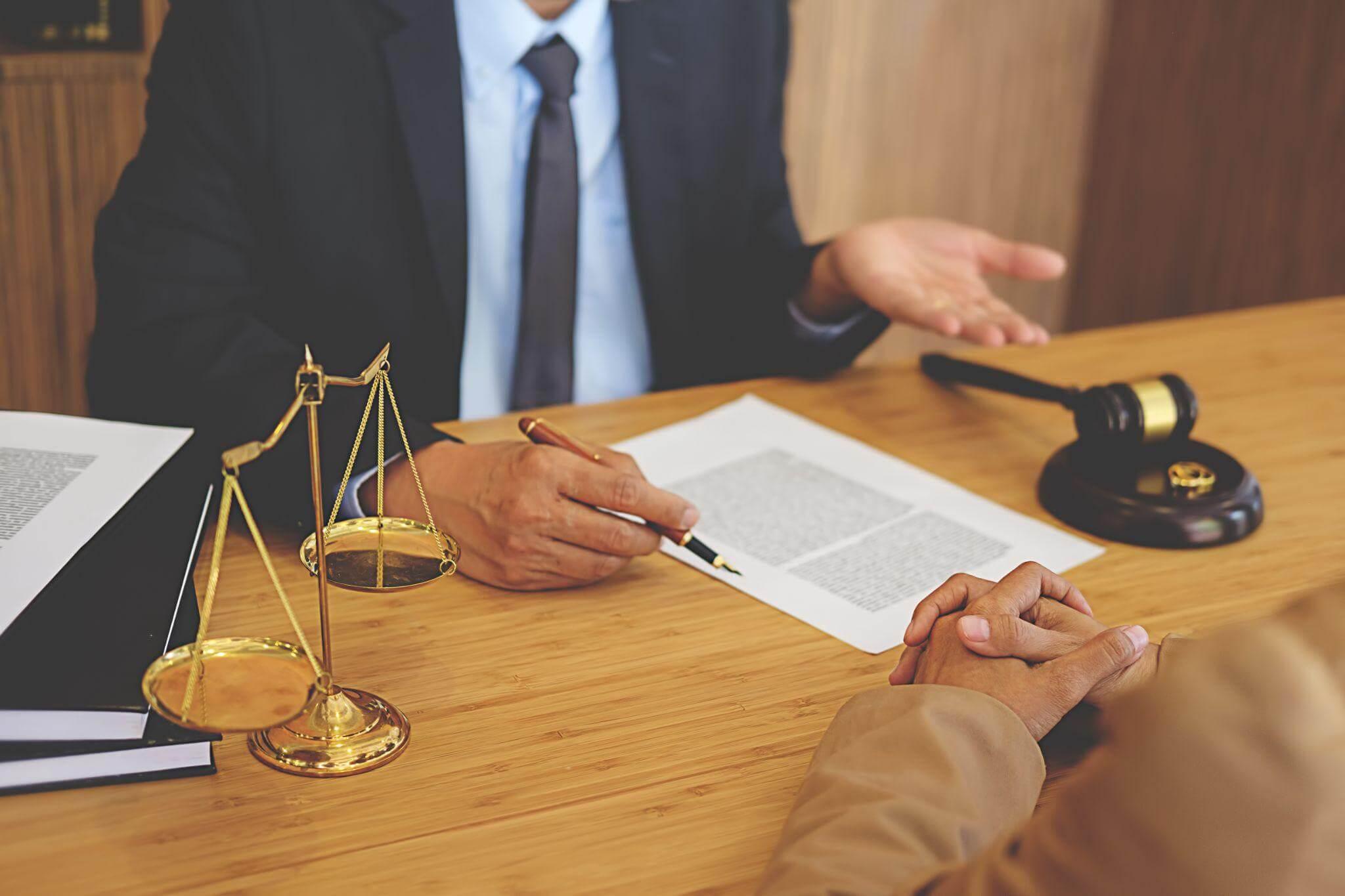 two people sitting at a table with a judge and a scale of justice