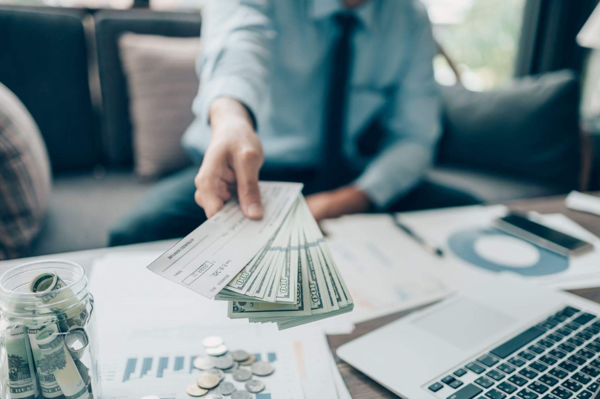a man sitting at a table with stacks of money in front of him